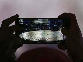 A spectator takes a picture of the opening ceremony of the 2018 Winter Olympics in Pyeongchang, South Korea, Friday, Feb. 9, 2018.