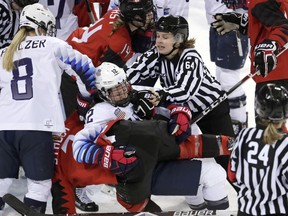 Official Jenni Heikkinen (64), of Finland, tries to separate Kelly Pannek (12), of the United States, and Laura Stacey (7), of Canada, as they scuffle during the third period of a preliminary round during a women's hockey game at the 2018 Winter Olympics in Gangneung, South Korea, Thursday, Feb. 15, 2018. Canada won 2-1.