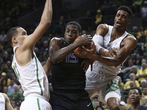 Oregon's Paul White, left, watches as temmate Kenny Wooten, right, works against Washington's Noah Dickerson for a rebound during the first half of an NCAA college basketball game Thursday, Feb. 8, 2018, in Eugene, Ore.