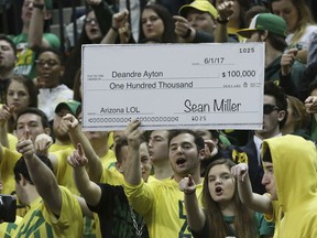 Fans in the Oregon student section hold up a sign making fun of the controversy surrounding Arizona coach Sean Miller, during the first half of an NCAA college basketball game Saturday, Feb. 24, 2018, in Eugene, Ore.