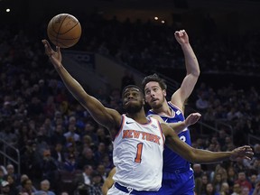 New York Knicks' Emmanuel Mudiay (1) and Philadelphia 76ers' T.J. McConnell (12) reach for loose ball in the first half of an NBA basketball game, Monday, Feb 12, 2018, in Philadelphia.