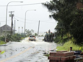 In this Friday, Feb. 9, 2018 photo, first responders with a backhoe work amid strong winds and heavy rain from Tropical Storm Gita to clear part of the main road at Fagaalu village in American Samoa. Officials in American Samoa began a full assessment Monday, Feb. 12, of damage caused by tropical storm Gita over the weekend.