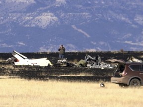 FILE--This Jan. 19, 2018, file image taken from video shows an investigator photographing the scene near Raton, N.M., where a helicopter crashed. The lone survivor of a New Mexico helicopter crash last month that killed five people, including key Zimbabwean opposition leader Roy Bennett, recalls that the aircraft hit the ground with a loud bang before rolling forward and coming to a stop upside down.