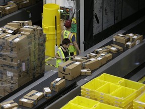 FILE- In this Feb. 9, 2018, file photo, packages move down a conveyor system to the proper shipping area at the new Amazon Fulfillment Center in Sacramento, Calif. The Environmental Protection Agency says it has reached a $1.2 million settlement with Amazon over the sale of illegal pesticides. The pesticides were sold by independent sellers who offered the products through Amazon's website.