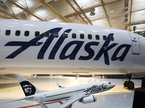 FILE - This Jan. 25, 2016, file photo,  the new logo of Alaska Airlines is shown next to a model of a plane with the old livery in Seattle. An Alaska Airlines flight to Seattle was forced to return to Anchorage, Alaska, early Wednesday, Feb. 7, 2018, after a passenger locked himself in the bathroom, took off all his clothes, and refused to follow crew instructions.