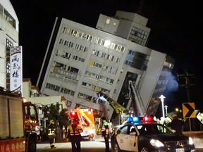 Rescuers enter a building that collapsed onto its side from an early morning 6.4 magnitude earthquake in Hualien County, eastern Taiwan, Wednesday, Feb. 7 2018.