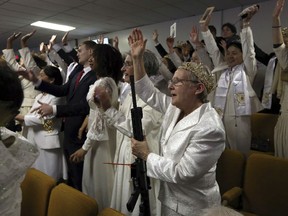 A woman wears a crown and holds an unloaded weapon as she cheers at the World Peace and Unification Sanctuary