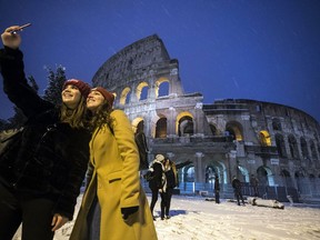 Two women take a selfie in front of the ancient Colosseum during a snowfall, early Monday, Feb. 26, 2018. Romans have awoken to a rare snowfall, after an Arctic storm passing over much of Europe dumped enough snow to force schools to close and public transport to reduce services.