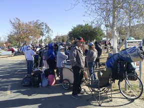 Homeless people line up in preparation to move from their homeless camp site along a riverbed in Anaheim, Calif. on Tuesday, Feb. 20, 2018. Authorities are being allowed to shut down a large homeless encampment in Southern California and move hundreds of tent-dwellers into motel rooms.