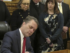 Kansas Gov. Jeff Colyer signs an executive order on sexual harassment as members of his Cabinet watch, Monday, Feb. 5, 2018, at the Statehouse in Topeka, Kan. The order requires thousands of executive branch employees to undergo annual sexual harassment training,