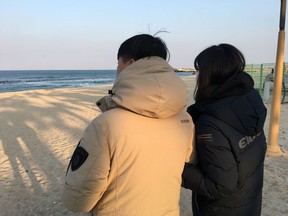 In this Feb. 8, 2018 photo, Lim Soo-young, right, a 45-year-old woman, looks at the ocean with her husband Kang Il-han after their interviews at Anmok Beach in Gangneung, South Korea. Lim said she hates North Koreans and considers those who came to South Korea for the Olympics as Kim's "puppets."