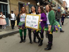 A group of women pose with a sign on Royal Street in the French Quarter on Friday, Feb. 2, 2018, as the two big weekends ahead of Mardi Gras kick off in New Orleans.