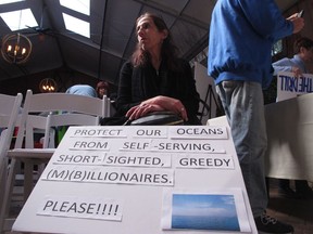 Jori Massef of South Brunswick sits with a sign protesting President Donald Trump's plan to allow offshore oil and gas drilling along most of the nation's coastline at a hearing Wednesday Feb. 14, 2018 in Hamilton, N.J. The hearing was one of many held by environmentalists and opponents of the drilling plan around the country before information sessions about the drilling plan held by the federal Bureau of Ocean Energy Management.