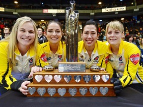 The Winnipeg rink including from left, skip Jennifer Jones, third Shannon Birchard, second Jill Officer and lead Dawn McEwen, gather around the championship trophy after winning the Scotties Tournament of Hearts Sunday in Penticton, B.C., defeating the wild card rink skipped by Kerri Einarson 8-6 in the final.
