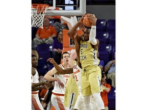 Georgia Tech's Josh Okogie, right, grabs a rebound while defended by Clemson's Marcquise Reed, left, during the first half of an NCAA college basketball game Saturday, Feb. 24, 2018, in Clemson, S.C.