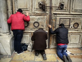 Visitors pray outside the closed doors of at the Church of the Holy Sepulchre, traditionally believed by many Christians to be the site of the crucifixion and burial of Jesus Christ, in Jerusalem, Sunday, Feb. 25, 2018. The leaders of the major Christian sects in Jerusalem closed the Church of the Holy Sepulchre, for several hours on Sunday to protest an Israeli plan to tax their properties.