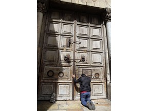A visitor stands outside the closed doors of at the Church of the Holy Sepulchre, traditionally believed by many Christians to be the site of the crucifixion and burial of Jesus Christ, in Jerusalem, Sunday, Feb. 25, 2018. The leaders of the major Christian sects in Jerusalem closed the Church of the Holy Sepulchre, for several hours on Sunday to protest an Israeli plan to tax their properties.