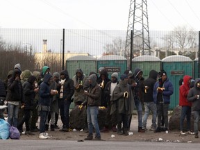 Migrants take a coffee and food provided by activists in Calais, northern France, Friday Feb.2, 2018. Police reinforcements are arriving in the French port city of Calais after clashes among migrants left 22 people injured, as the interior minister warned of a worrying spike in violence.