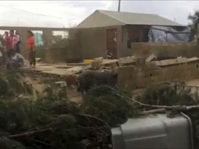 In this image made from a video, people stand near a house damaged by Cyclone Gita in Nuku'alofa, Tonga Tuesday, Feb. 13, 2018. Tonga began cleaning up Tuesday after a cyclone hit overnight, while some people in the nearby Pacific nation of Fiji began preparing for the storm to hit them. (TVNZ via AP)