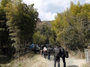 Journalists gather near the site where a body part believed to be of a missing woman was found in Osaka, western Japan Monday, Feb. 26, 2018. Media reports said police last week arrested the suspected man, Yevgeniy Vasilievich Bayraktar, 26, from New York, on suspicion of confining the missing Japanese woman at his lodging in Osaka. Reports said Monday police are investigating his possible link to dismembering and abandoning of her body after finding other body parts.