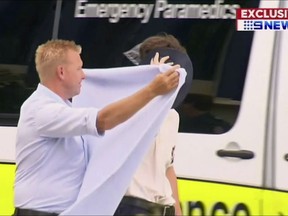 In this Wednesday, Feb. 21, 2018, image made from video, a student is shielded as heading to an ambulance near Gold Coast city, Australia. Five boys remained in an Australian hospital on Thursday, a day after suffering drug overdoses at a private school. (Channel 9 via AP)