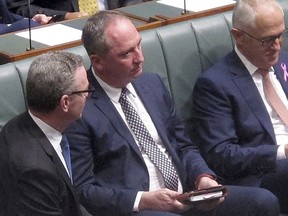 FILE - In this Feb. 15, 2018 file photo, Australian Deputy Prime Minster Barnaby Joyce, center, sits with colleagues including Prime Minister Malcolm Turnbull, right, during a session in the Australian Parliament in Canberra. Australia's beleaguered deputy prime minister has resigned from Cabinet over an allegation that he sexually harassed a woman. But Joyce said on Friday, Feb. 23, he will not resign from Parliament, ensuring that Prime Minister Malcolm Turnbull's single-seat majority in the House of Representatives is maintained.