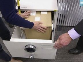 This image made from video provided by the Australian Broadcasting Corp., (ABC) shows documents box being placed in safe at the ABC bureau in the Australian Parliament House in Canberra, Thursday, Feb. 1, 2018.  Australian secret service officers on Thursday, Feb. 1, 2018,  secured thousands of classified documents that were sold with two secondhand filing cabinets and have been the basis of news reports by Australia's national broadcaster.  (Australian Broadcasting Corp via AP)