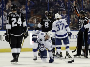 Tampa Bay Lightning defenseman Mikhail Sergachev (98) gets up after being taken down by Los Angeles Kings right wing Dustin Brown (not shown) during the second period of an NHL hockey game Saturday, Feb. 10, 2018, in Tampa, Fla. Brown was kicked out of the game for the hit. Kings defensemen Derek Forbort (24) and Drew Doughty (8) skate past.