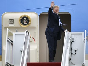 Donald Trump waves from the top of the steps of Air Force One at Andrews Air Force Base in Md., Friday, Feb. 16, 2018.