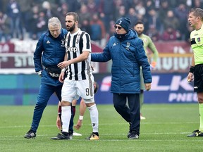 Juventus's Gonzalo Higuain, center, leaves the pitch after being injured during the Italian Serie A soccer match between Torino and  Juventus at Turin's Olympic Stadium, Italy, Sunday Feb.18, 2018.