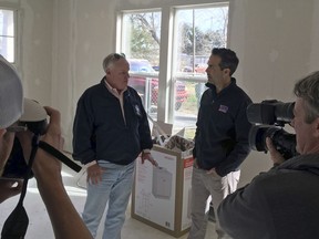 In this Jan. 30, 2018, photo, Texas Land Commissioner George P. Bush, right, and the Federal Emergency Management Agency's Hurricane Harvey Coordinator, Kevin Hannes, left, are surrounded by local media in Nome Texas, while discussing a home damaged in the storm that is being repaired using federal funds. Republican Texas Gov. Greg Abbott tasked Bush's agency with overseeing housing recovery needs after Harvey _ but nearly six months later, victim frustration is growing amid frequent delays and bureaucratic hurdles.