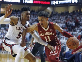 Oklahoma's Trae Young (11) dribbles the ball around Texas Tech's Justin Gray (5) during an NCAA college basketball game Tuesday, Feb. 13, 2018, in Lubbock, Texas.