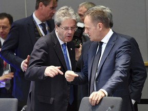 Italian Prime Minister Paolo Gentiloni, left, speaks with European Council President Donald Tusk during a round table at an EU summit at the Europa building in Brussels on Friday, Feb. 23, 2018. European Union leaders meet without Britain Friday looking to plug a major budget hole after Brexit and endorse a plan to streamline the European Parliament by sharing out the country's seats.