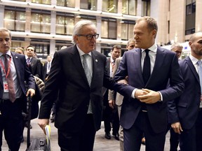 European Commission President Jean-Claude Juncker, center left, and European Council President Donald Tusk, center right, walk together to a media conference at the end of an EU summit at the Europa building in Brussels on Friday, Feb. 23, 2018. European Union leaders met without Britain Friday looking to plug a major budget hole after Brexit and endorse a plan to streamline the European Parliament by sharing out the country's seats.