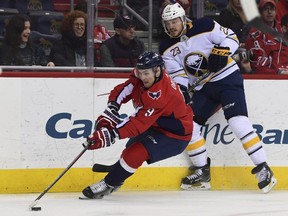 Washington Capitals defenseman Dmitry Orlov (9), of Russia, moves the puck around Buffalo Sabres center Sam Reinhart (23) during the first period of an NHL hockey game in Washington, Saturday, Feb. 24, 2018.