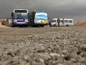 Members of the Syrian government forces stand near buses at the Wafideen checkpoint on the outskirts of Damascus neighbouring the rebel-held Eastern Ghouta region on February 27, 2018.