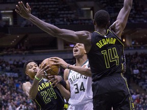 Milwaukee Bucks forward Giannis Antetokounmpo, center, is defended by Atlanta Hawks guard Kent Bazemore, left, and Dewayne Dedmon, right, during the first half of an NBA basketball game Tuesday, Feb. 13, 2018, in Milwaukee.