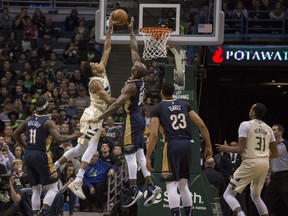 Milwaukee Bucks forward Giannis Antetokounmpo, left, gets a slam dunk over New Orleans Pelicans center Emeka Okafor, right, during the first half of an NBA basketball game Sunday, Feb. 25, 2018, in Milwaukee.