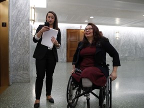 Sen. Tammy Duckworth, D-Ill., right, waits with an aide for the elevator on Capitol Hill, Wednesday, Feb. 14, 2018 in Washington. Duckworth doesn't blend in, and that's the way she likes it. The decorated Iraqi War veteran who lost both legs when her helicopter was shot down is an Asian-American woman in the mostly-white, mostly-male and very fusty Senate. And now, with a baby due in April, the Illinois Democrat will be the first senator to give birth while in office.