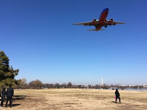 In this Jan. 26, 2018, photo, people watch a commercial passenger jet fly over Gravelly Point Park as it comes in to land at Ronald Reagan Washington National Airport in Arlington, Va., across the Potomac River from the nation's capital. In one of Virginia's most liberal jurisdictions, political leaders are just saying 'no' to a proposal in Congress to name a popular park for former first lady Nancy Reagan. Legislation passed a House committee last month to rename Gravelly Point Park, which sits on federal land adjacent to Ronald Reagan National Airport, for the former first lady. The bill's sponsor, Georgia Republican Jody Hice, says the change "would be a fitting tribute, given its proximity to Reagan National Airport." The proposal, though, is not supported by political leaders in Arlington County, where the park is located.