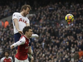 Tottenham Hotspur's Harry Kane, top, leaps above Arsenal's Laurent Koscielny as he scores the opening goal of the game during the English Premier League soccer match between Tottenham Hotspur and Arsenal at Wembley stadium in London, Saturday, Feb. 10, 2018.