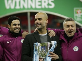 Manchester City's manager Pep Guardiola, centre poses for photographers as he celebrates after his team won the English League Cup defeating Arsenal 3-0 in the final at Wembley stadium in London, Sunday, Feb. 25, 2018.