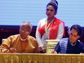 Myanmar's leader Aung San Suu Kyi, right, and Myanmar's President Htin Kyaw, left, signs documents during a ceasefire agreement at the Myanmar International Convention Center in Naypyitaw, Myanmar, Tuesday, Feb. 13, 2018. Two ethnic rebel groups have joined Myanmar's long-delayed peace process, a small step forward in ending decades of civil strife, but one that may not be significant.