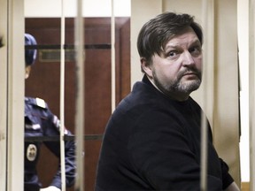 In this photo taken on Thursday, Feb. 1, 2018, former Kirov regional Gov. Nikita Belykh, who has been in custody since his June 2016 arrest while accepting money at a Moscow restaurant, stands in a cage in a court room in Moscow, Russia. A court in Moscow has convicted a former provincial governor of taking a 400,000-euro ($500,000) bribe and sentenced him to eight years in prison.