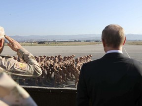 FILE - In this file photo taken on Tuesday, Dec. 12, 2017, Russian President Vladimir Putin, right, watches the troops marching as he and Syrian President Bashar Assad visit the Hemeimeem air base in Syria. Several private Russian military contractors were killed by a U.S. strike in Syria, Russian media reported Tuesday, Feb. 13, 2018 in a development that could further inflame Russia-U.S. tensions if officially confirmed.