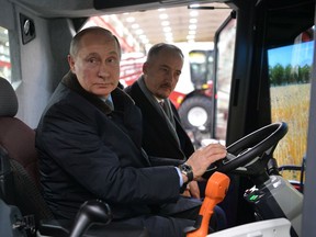 Russian President Vladimir Putin, foreground, sits inside a combine machine as he visits Rostselmash, a Russian agricultural equipment company in Rostov-on-Don, Russia, Thursday, Feb. 1, 2018.