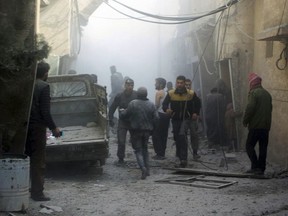 Members of the Syrian Civil Defense group and civilians gathering to help survivors from a street attacked by airstrikes and shelling by Syrian government forces, in Ghouta, a suburb of Damascus, Syria.