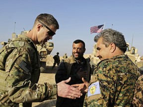 FILE - This Wednesday, Feb. 7, 2018 file photo, shows U.S. Army Maj. Gen. Jamie Jarrard left, thanks Manbij Military Council commander Muhammed Abu Adeel near the town of Manbij, northern Syria. As Syrian troops and their allies push toward final victory and the battle against Islamic State militants draws to an end, new fronts are opening up, threatening an even broader confrontation. The U.S., Israel and Turkey all have deepened their involvement, seeking to protect their interests in the new Syria order.