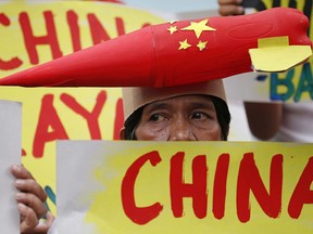 A protester wears a mock missile on her head during a rally at the Chinese Consulate to protest China's alleged continued militarization of the disputed islands in the South China Sea known as Spratlys Saturday, Feb. 10, 2018 in the financial district of Makati city east of Manila, Philippines. The protesters also denounced President Rodrigo Duterte's inaction over China's continued build up of military facilities and structures at the disputed islands.