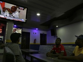 People watch a public live broadcast on television of President Jacob Zuma being interviewed on state television in Pretoria, South Africa, Wednesday, Feb. 14, 2018. The speaker of South Africa's parliament wants to hold a motion of no confidence in Zuma on Thursday afternoon. saying the timing of the vote by open ballot must be agreed upon by the parliament's program committee later Wednesday. Both the ruling African National Congress party and opposition parties are pushing for a parliamentary vote against Zuma, who has not responded to an order from his own party to leave office.